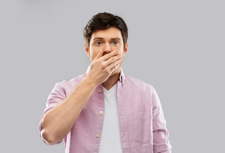 Wegen eines abgebrochener Zahns hält sich ein Mann die Hände vor den Mund.
