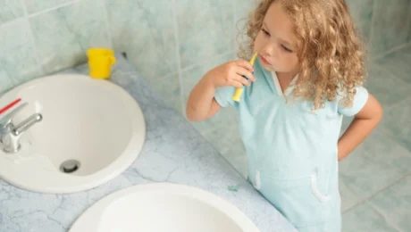 Das Kind zeigt, wie man richtig Zähne putzen kann.