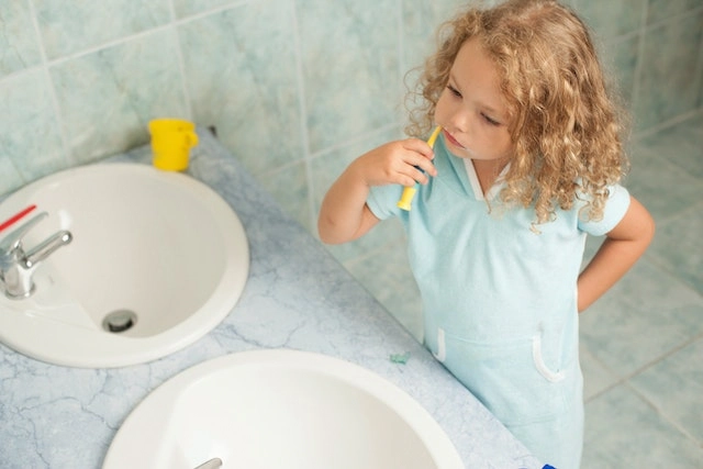 Das Kind zeigt, wie man richtig Zähne putzen kann.